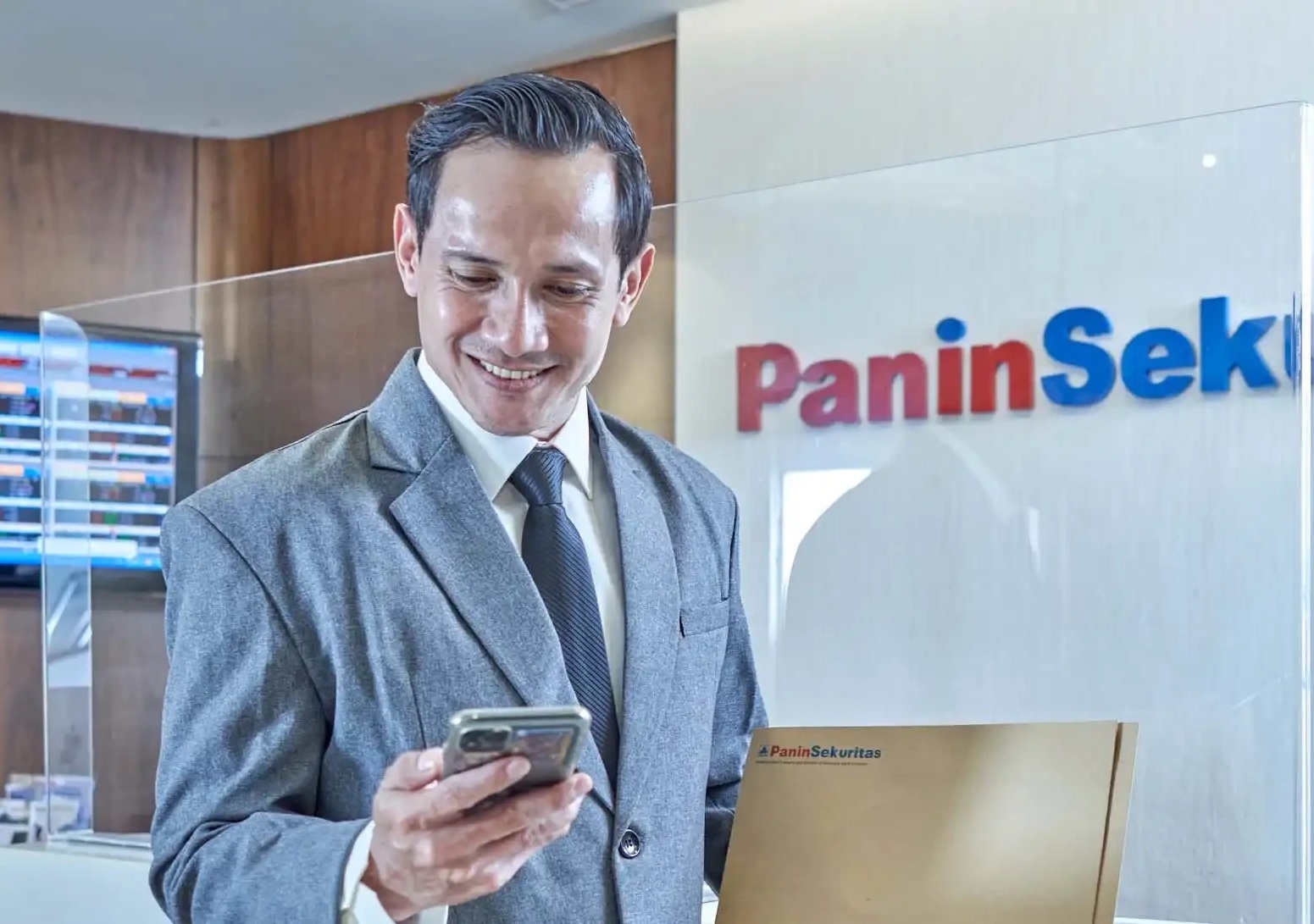 Seorang investor tampak serius memelototi pergerakan saham via telepon pintar. FOTO - ISTIMEWA Laba dan Pendapatan Melorot, Simak Detail Kinerja PANS Semester I 2025